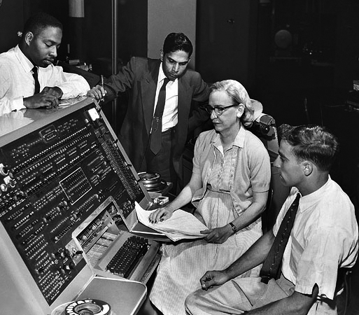 Grace Hopper diante de um teclado UNIVAC com colegas do departamento de programação automática em 1957